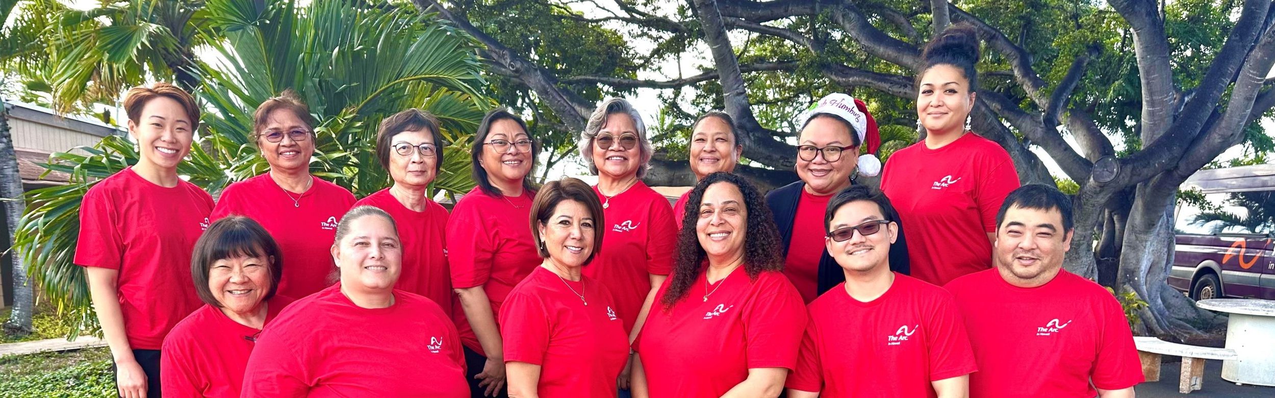 A group of 12 people wearing matching red shirts.
